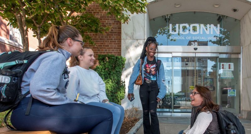 Four students sitting outside of the school of social work building